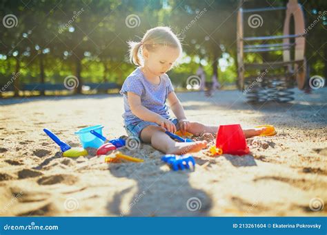 Adorable Little Girl Having Fun On Playground In Sandpit Stock Photo