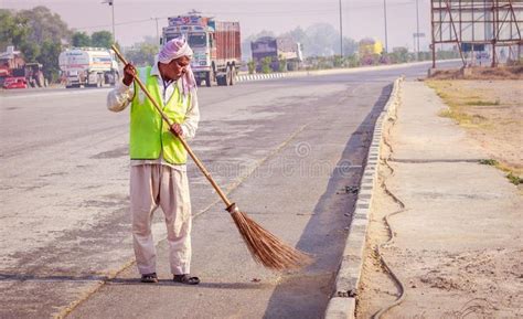 An Old Man Sweeping The Street With A Broom In India Stock Images And
