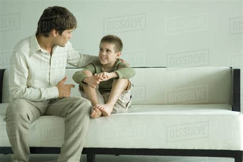 Father And Son Sitting On Sofa Talking Stock Photo Dissolve