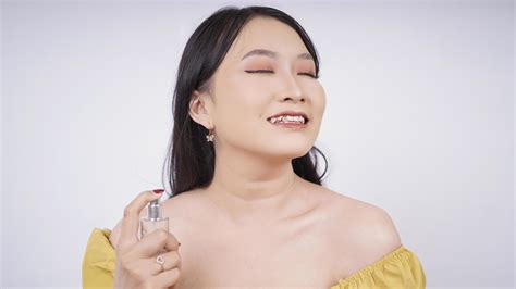 Belle Fille Asiatique Pulvérise Du Parfum Sur Son Lit Isolé Sur Fond
