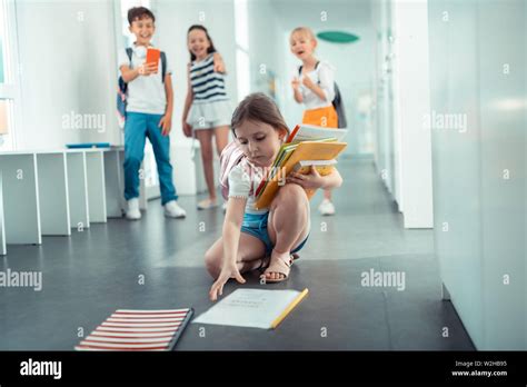 Girl Picking Up Books From Floor After Boy Pushed Her Stock Photo Alamy