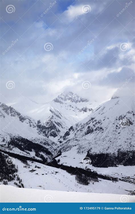 Snowy Ski Slope In High Mountains And Cloudy Sunlit Sky At Winter