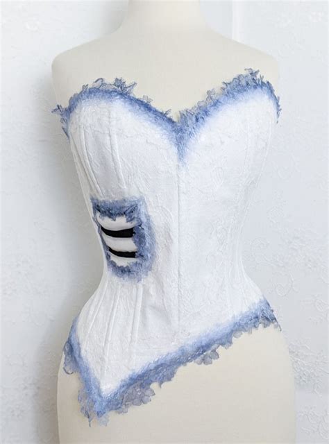 A White Corset With Blue And Black Trimmings On The Bust Sitting On A