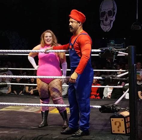 A Man Standing Next To A Woman In A Wrestling Ring