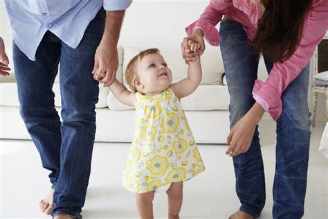 Parents teaching baby girl to walk - Children's Support ...