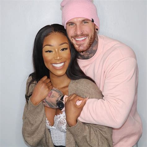 A Man And Woman Hugging Each Other In Front Of A White Wall With A Pink