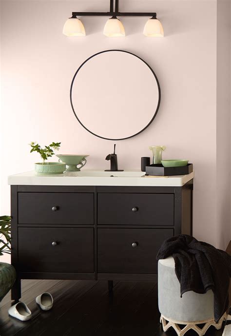 A Bathroom Vanity With Two Lights And A Mirror On The Wall Next To It