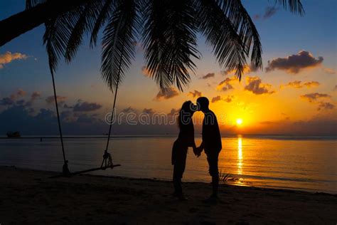 Silhouetted Couple In Love Kisses On The Beach During Sunset Stock