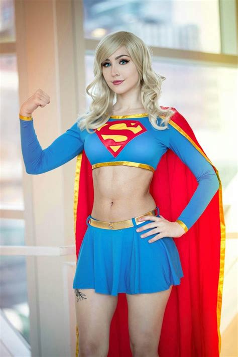 A Woman Dressed As A Supergirl Posing For The Camera With Her Hands On Her Hips