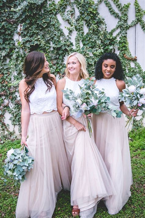 Three Bridesmaids Standing In Front Of A Ivy Covered Wall Holding