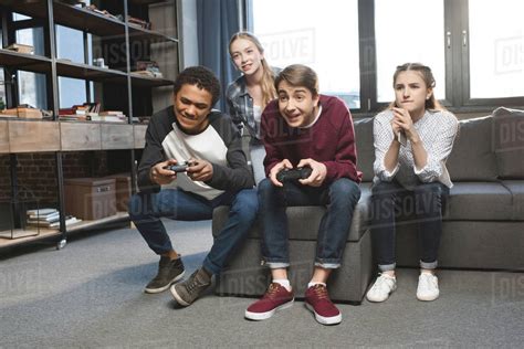 Happy Multicultural Teenagers Playing Video Games With Joysticks At