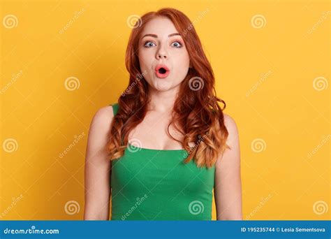 Astonished Young Woman With Wavy Red Hair Looking Directly At Camera