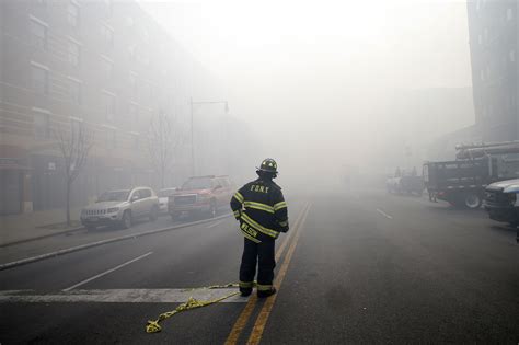 A Firefighter Stands In Smoke Filled East 116th Street Near An Apparent