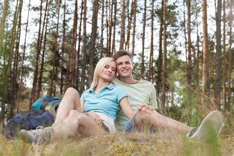 Full Length Of Romantic Young Hiking Couple Relaxing In Forest