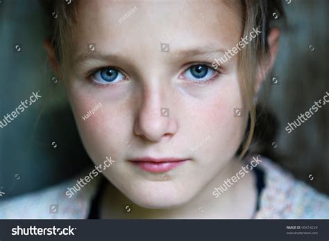 Sad Little Girl Is Looking With Serious Face At Camera Stock Photo