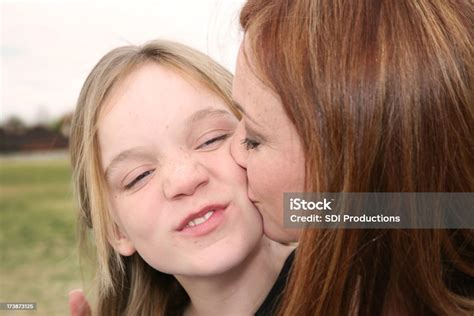 Mother Kissing Her Daughter On The Cheek Stock Photo Download Image