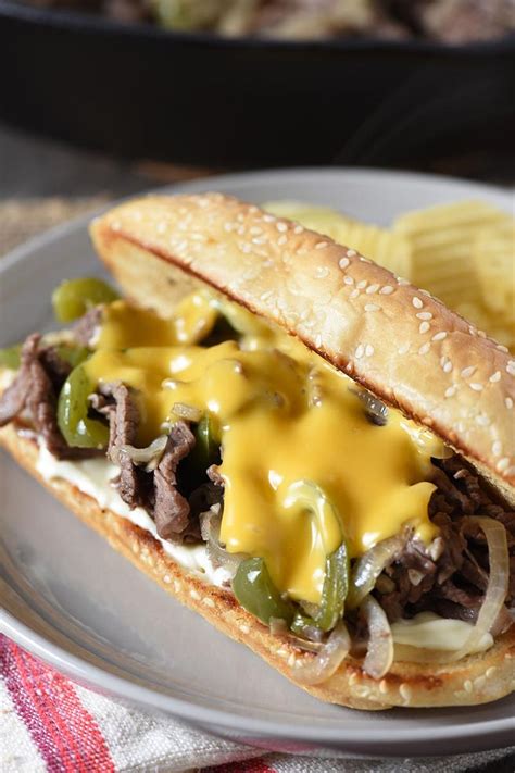 A Cheese Steak Sandwich On A Plate With French Fries