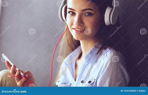 Muchacha Sonriente Con Los Auriculares Que Se Sientan En El Piso Foto