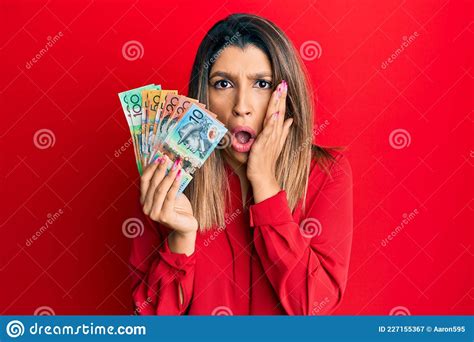 Beautiful Brunette Woman Holding Australian Dollars Afraid And Shocked Surprise And Amazed
