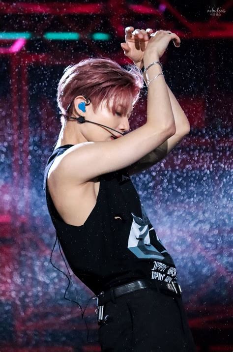 a woman with red hair and piercings on her ear standing in front of a rain shower