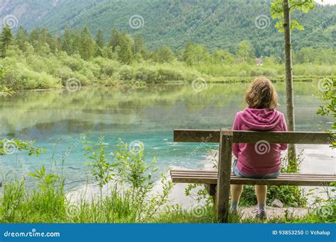 Woman Is Sitting On Bench Near Lake In Austria Near Alps Stock Photo