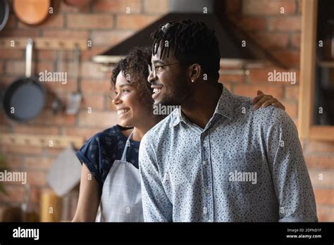 Happy Young Bonding African American Couple Dreaming Indoors Stock