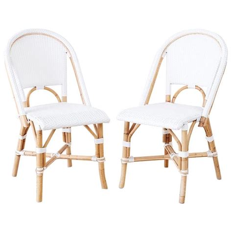 Two White Wicker Chairs Sitting Next To Each Other On Top Of A White Floor