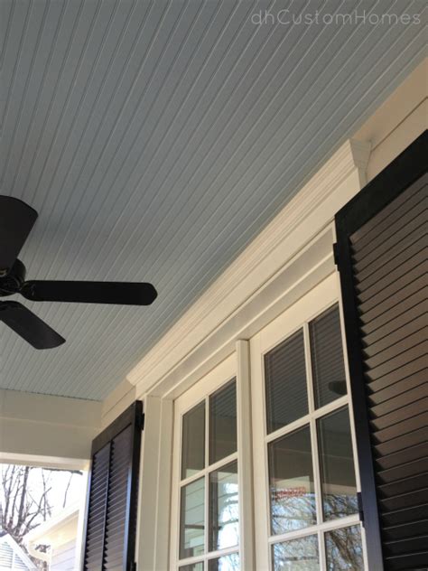 Gorgeous cottage porch features a gray wash porch swing sofa hanging by ropes from a white beadboard ceiling and topped with a light gray cushion and white border gray white border pillows accented by a matching accent chair sat. Homewood in Kirkwood - Front Porch Beadboard Ceiling - DH ...