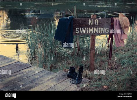 No Swimming Sign By A Pond With Vintage Clothes Hanging From Sign Stock