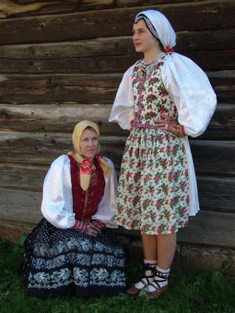 Two Women Dressed In Folk Clothing Standing Next To Each Other