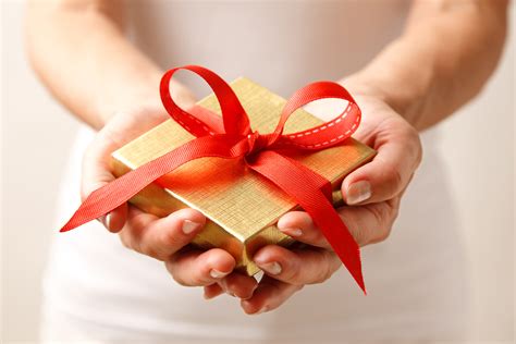 Woman holding a gift box in a gesture of giving.
