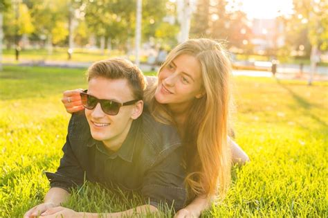 Atractiva Pareja De Adolescentes Tumbados En La Hierba Sonriendo Y Divirtiéndose Foto Premium