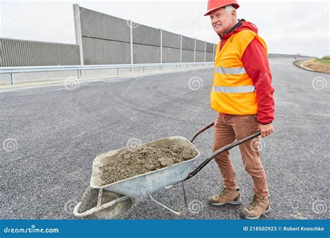 Construction Worker With Wheelbarrow Full Of Concrete On Construction