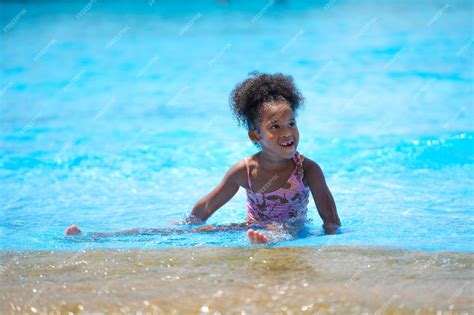 fille africaine assise et jouant de l eau dans la piscine du parc d attractions photo premium