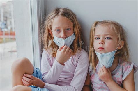 Twee Kleine Zussen Met Maskers Op Hun Gezichten Kijken Uit Het Venster
