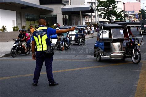 A Traffic Enforcer Directs Traffic To Vehicles At A Busy Intersection
