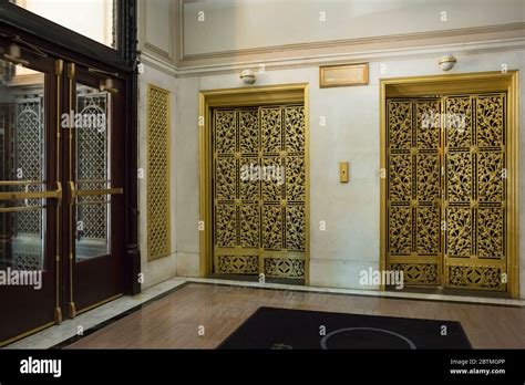 Horizontal view of two profusely decorated gold elevators at the Fisher