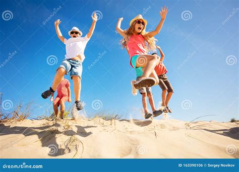 Group Of Children Jump Up From Sand Dune Stock Photo Image Of
