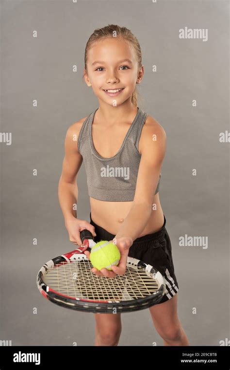 Adorable Girl Tennis Player With Racket And Ball Looking At Camera And