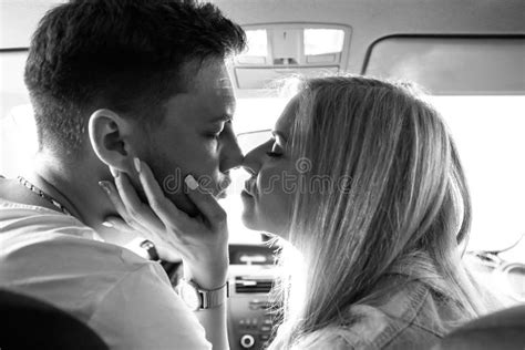 pares en la sentada que se besa del hombre y de la mujer del amor en el coche imagen de archivo