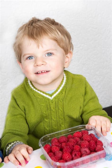 Adorable Toddler Boy With Blond Hairs Eating Fresh Raspberries A Stock