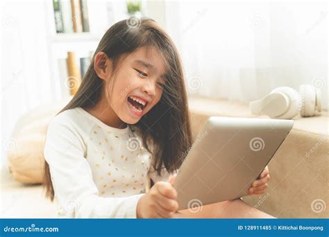 Asian Cute Child Playing Games With A Tablet And Smiling While Stock