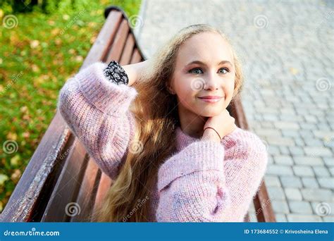 Pretty Teenage Girl 14 16 Year Old With Curly Long Blonde Hair In The Green Park On The Bench In