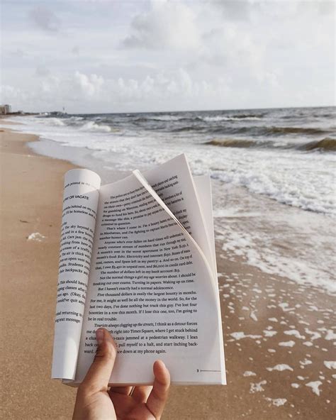 Someone Is Holding An Open Book On The Beach
