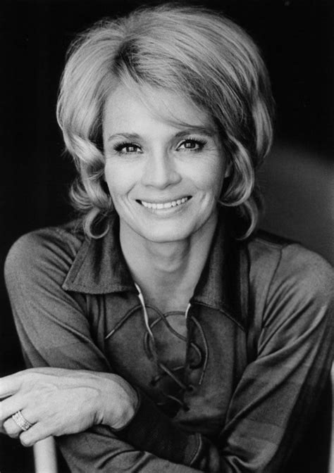 A Black And White Photo Of A Smiling Woman With Her Arms Folded Over Her Chest