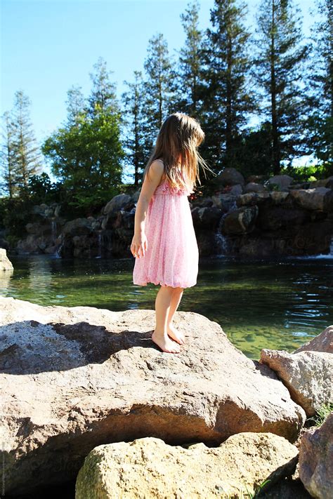 Girl In Pink Dress Standing On Rocks Near Tall Trees By Stocksy Contributor Dina Marie