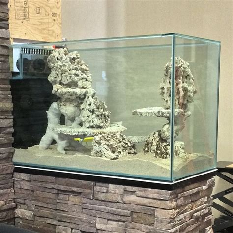 A Fish Tank Filled With Rocks And Water Next To A Fire Place In A