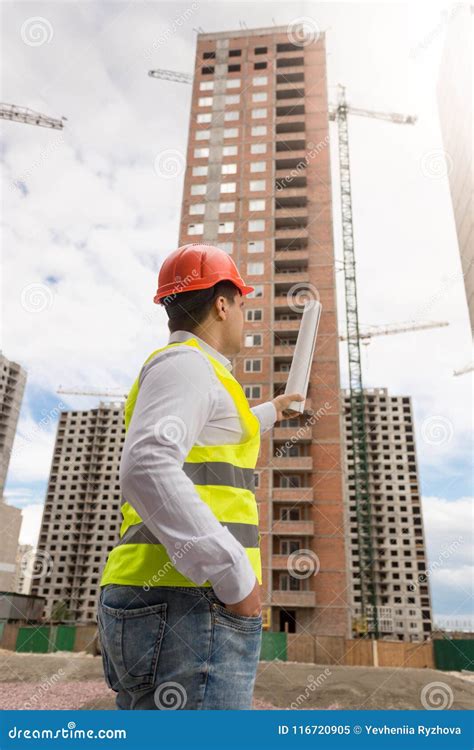 Male Building Engineer In Hardhat Pointing At Construction Site With