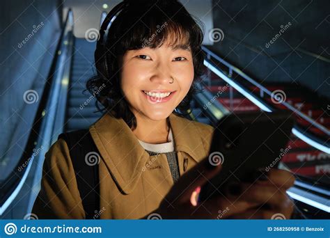 Close Up Of Cute Asian Girl In Headphones Picks Song To Listen While