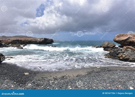 Waves Rolling Onto The Black Sand Stone Beach In Aruba Stock Photo
